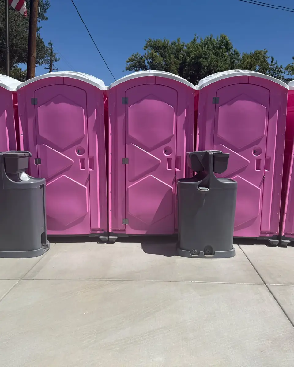 Event portable toilets with hand wash stations on pavement in bright sun