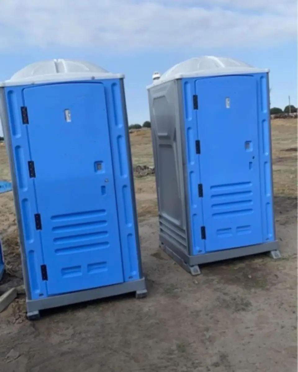 Two portable toilets on an open job site