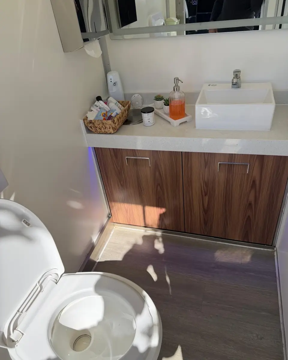 Restroom trailer vanity with a vessel sink, wood cabinet, mirror and hand towels