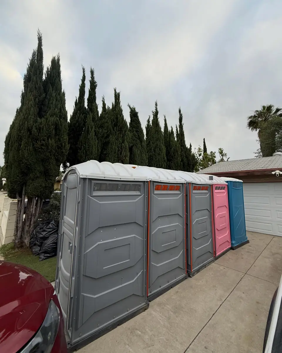 Row of portable toilets along a fence line at a work site